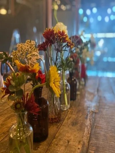 Warm amber glass vases with seasonal blooms and wildflowers — rich, glowing, and beautifully textured.