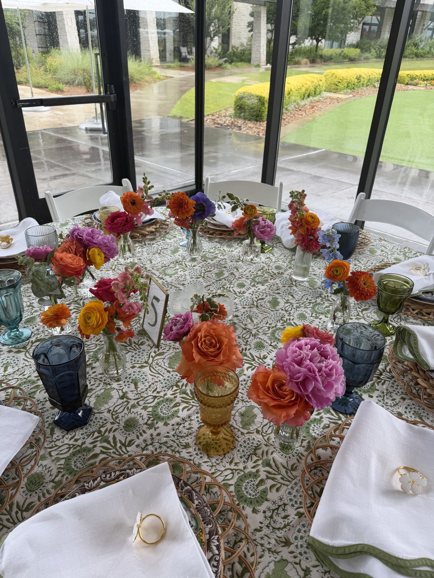 A curated mix of seasonal blooms across bud vases and vintage glassware — joyful, personal, and full of character.