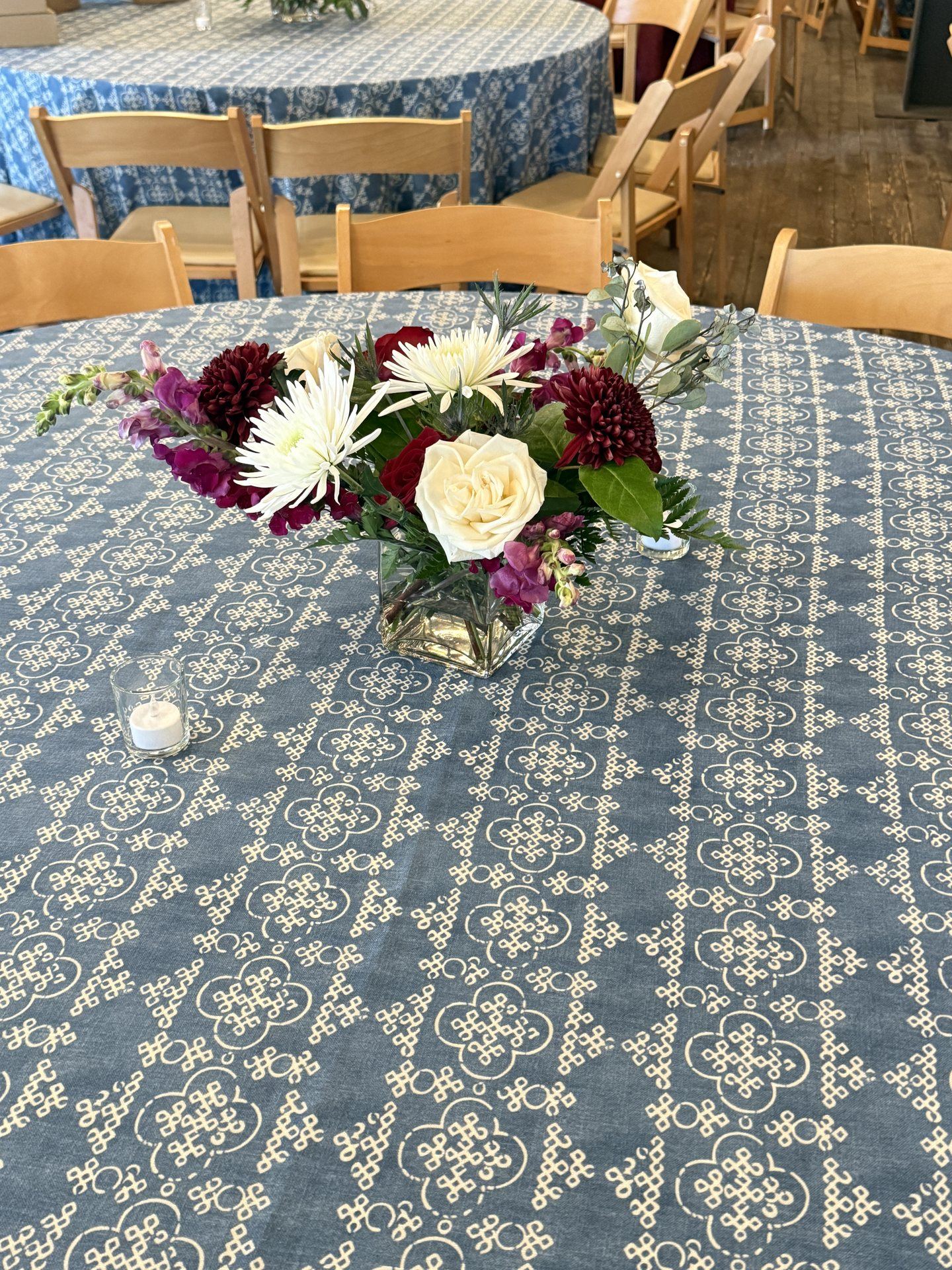 Burgundy dahlias, ivory roses, and magenta snapdragons in a low compote — an editorial statement for elevated evening events.