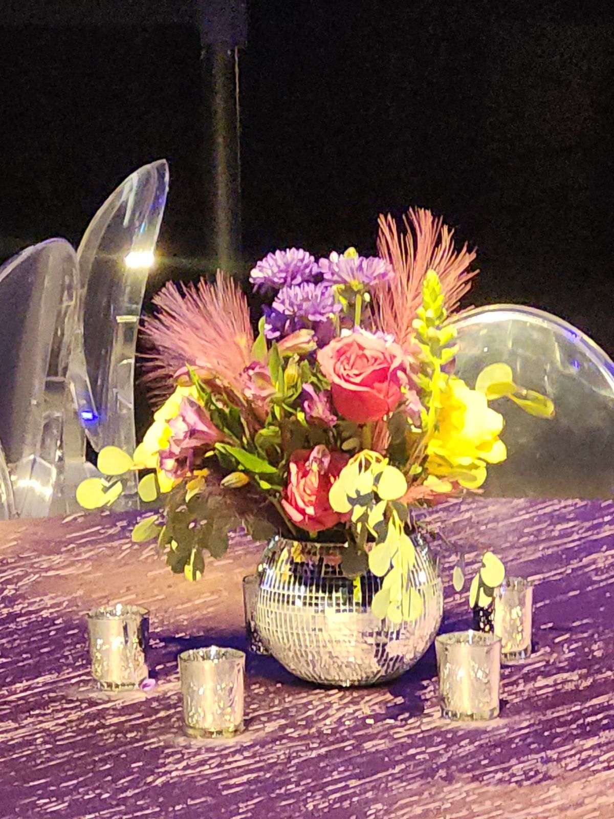 Roses, asters, and feathered grasses bursting from a disco-ball vase over sequined linen — florals for the after-party.