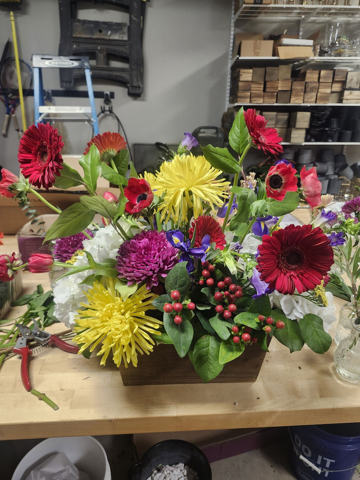 Red gerberas, spider mums, iris, and hypericum packed into a wooden bloom box — saturated color for celebrations.