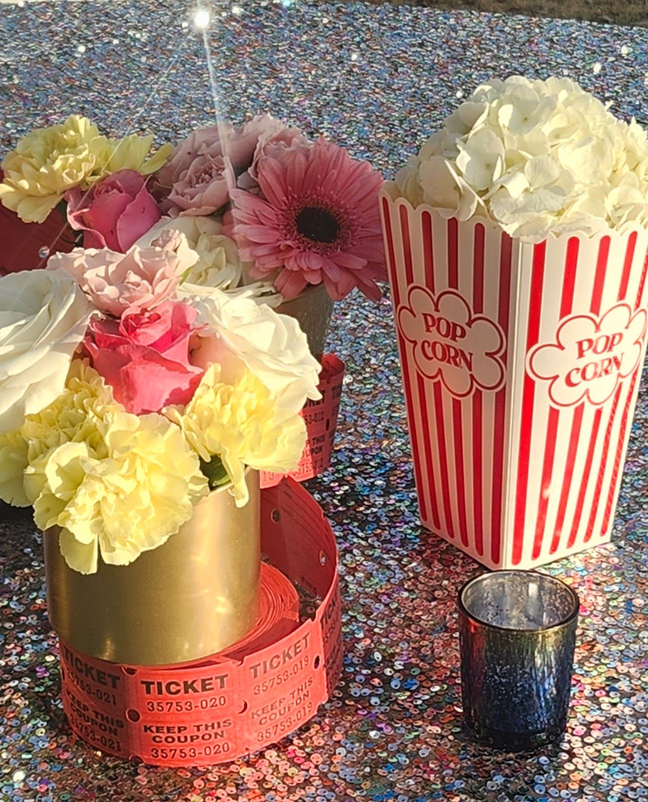 Hydrangea 'popcorn' spilling from striped boxes and roses ringed in ticket rolls — themed florals for a premiere night.