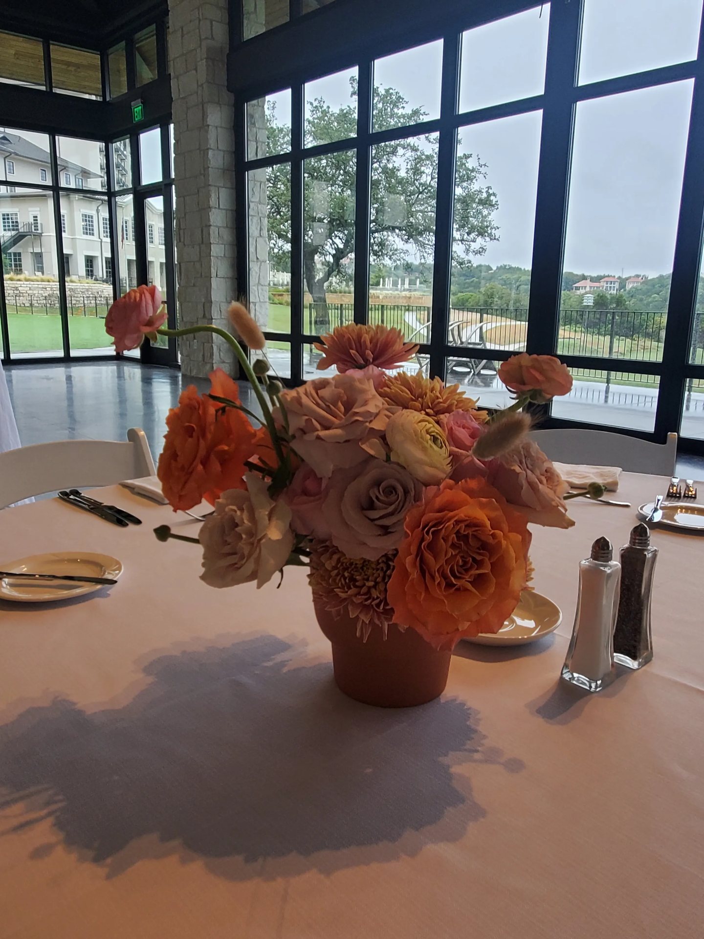 Neutral roses and ranunculus centerpiece by a window at an Austin venue