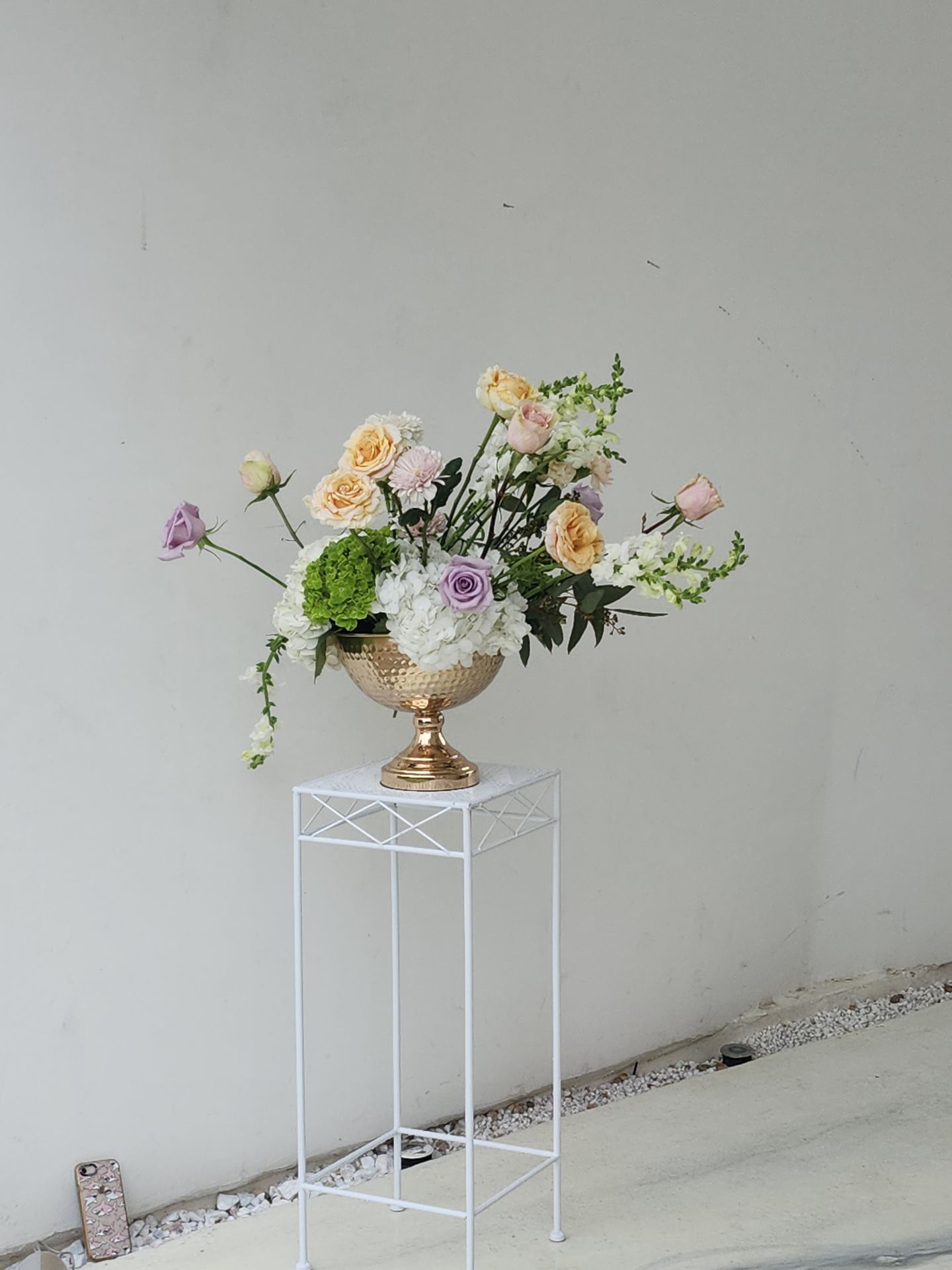 Peach and lavender roses in a hammered gold compote on a ceremony pedestal