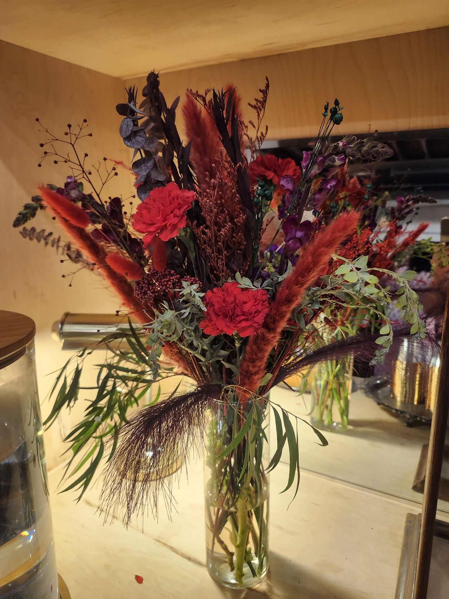 Bunny tails, preserved eucalyptus, and red carnations in rich autumn tones — a statement piece that lasts long after the event.